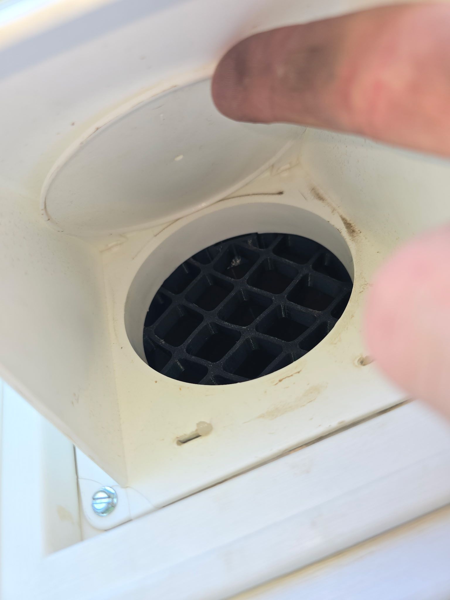 A person's hand is reaching into a hole in a white box