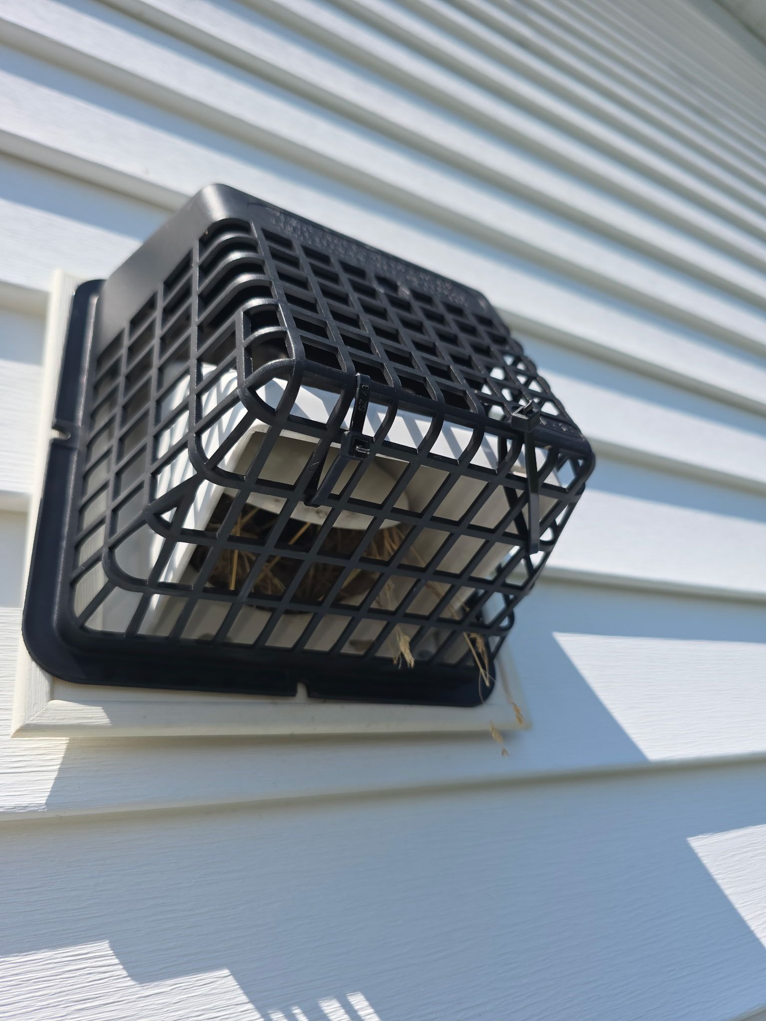 A black vent guard on the side of a house