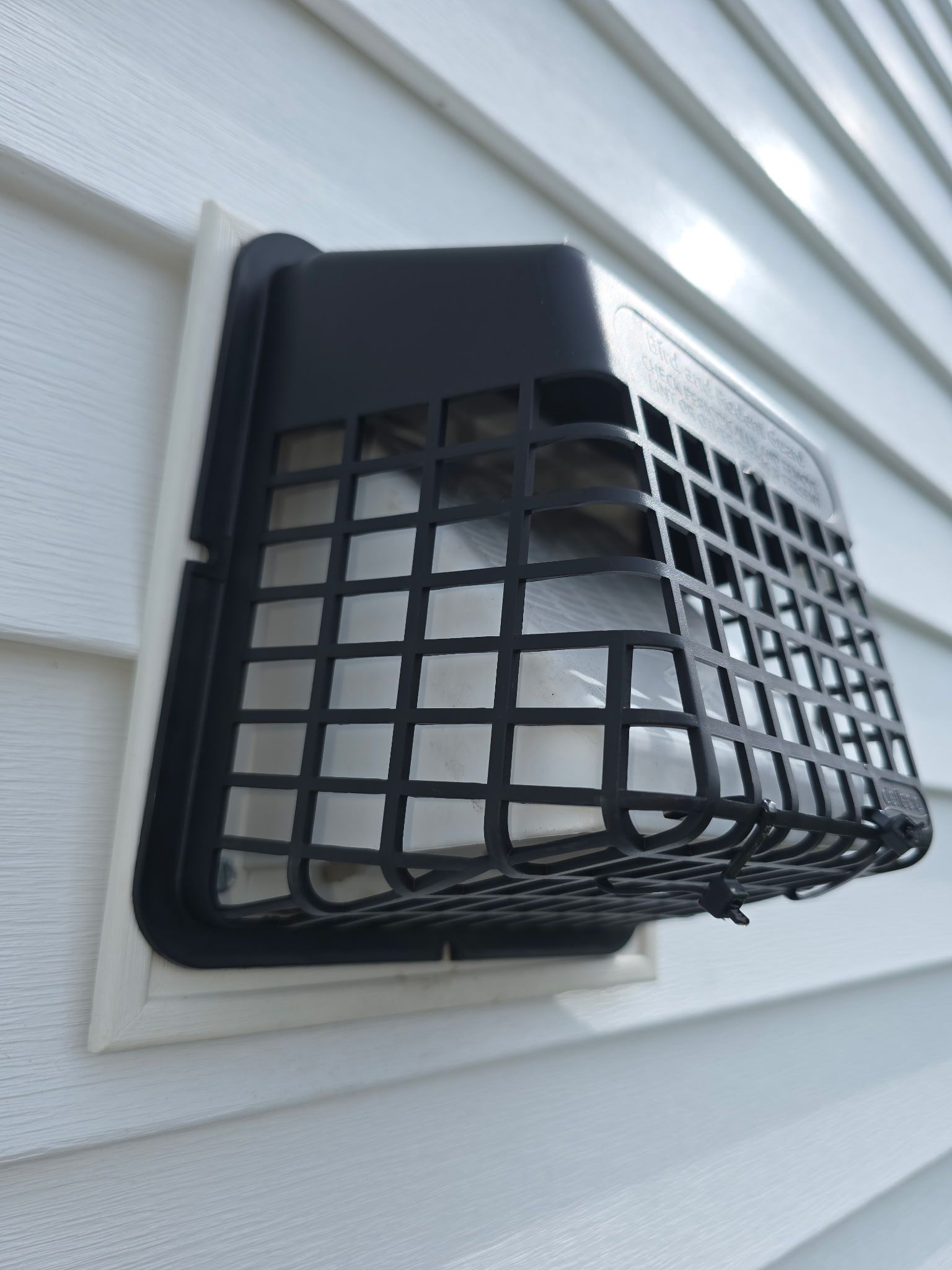 A white siding with a black vent guard on it