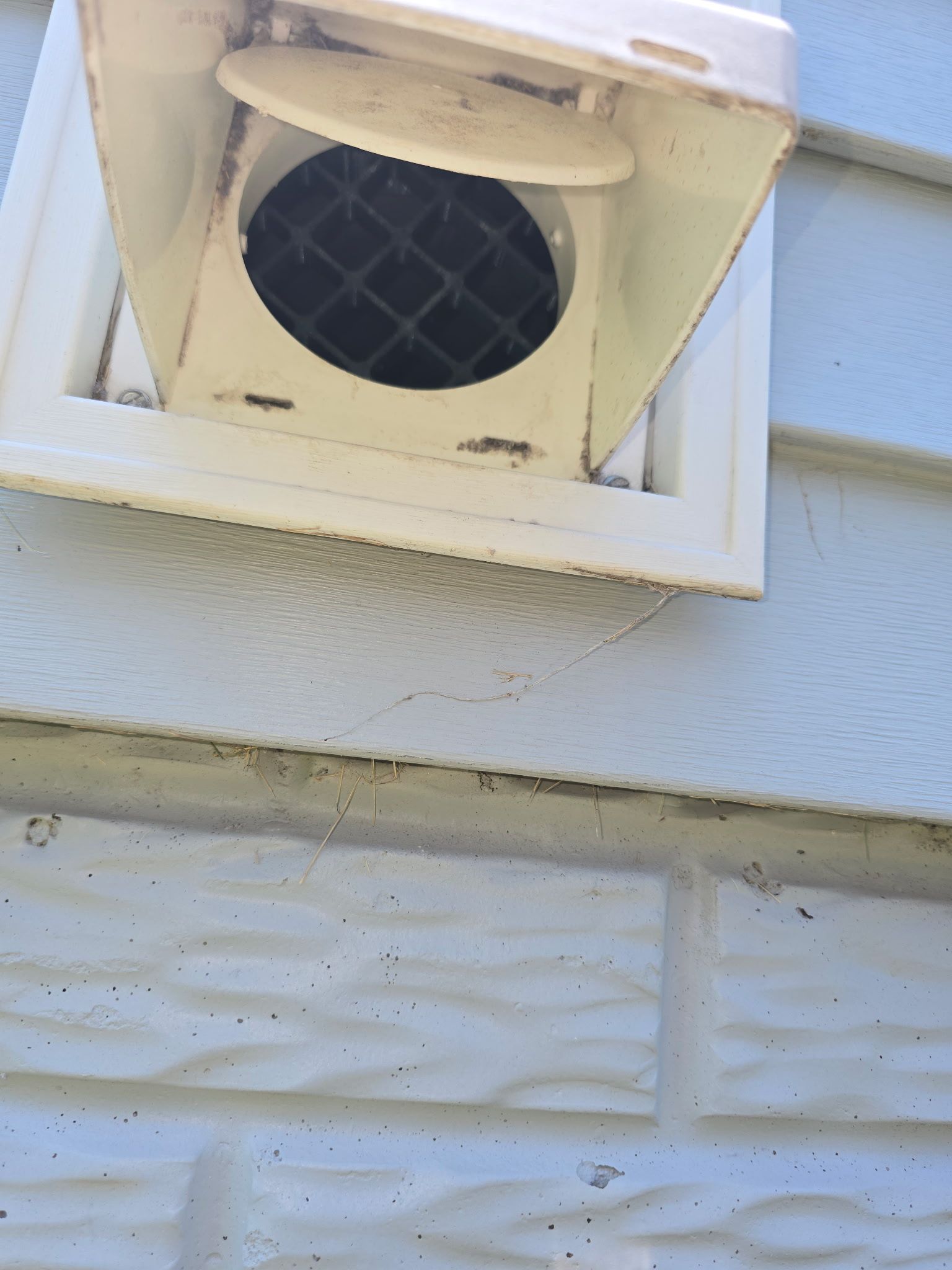 A white vent on the side of a building