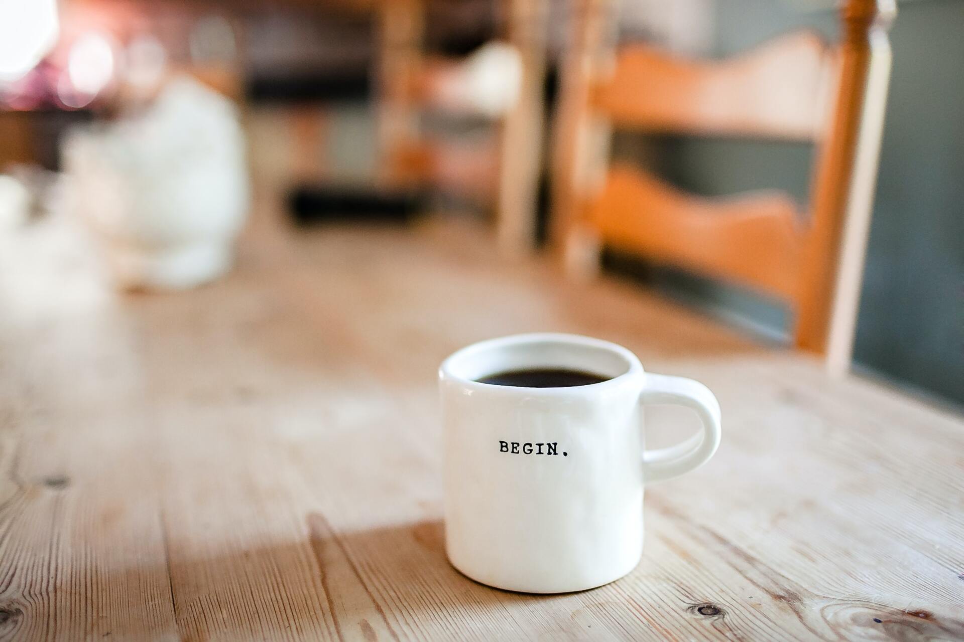 A cup of coffee is sitting on a wooden table.