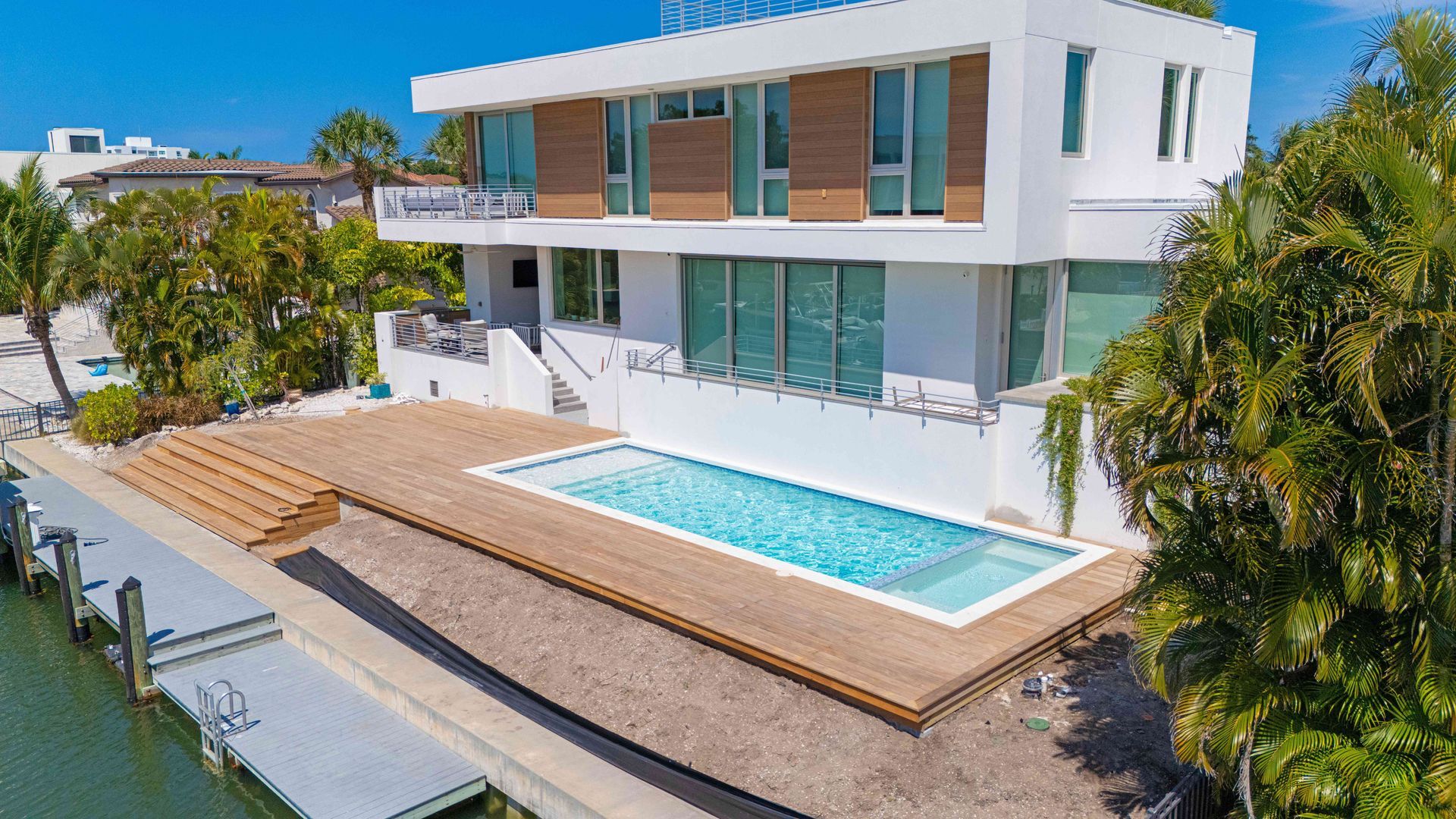 Modern white beach house with wooden deck and swimming pool beside the shoreline