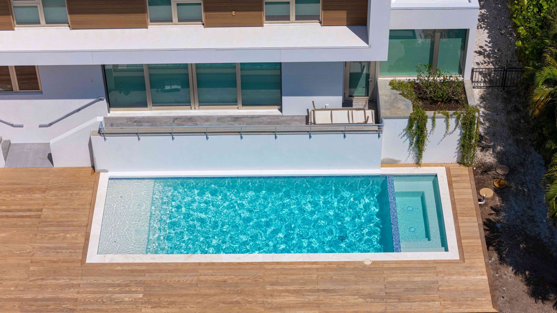 Modern house patio with a rectangular swimming pool and wooden deck.