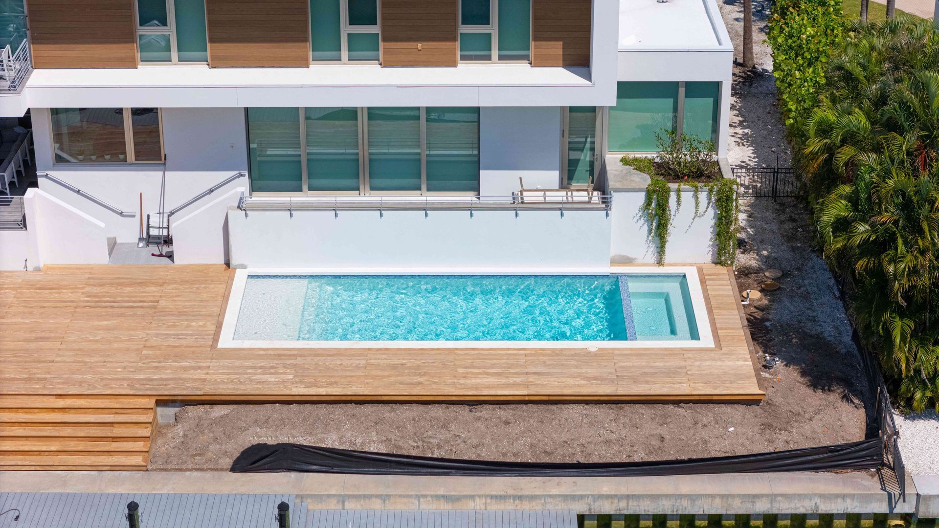 Modern house with a wooden deck and a narrow turquoise swimming pool in the backyard