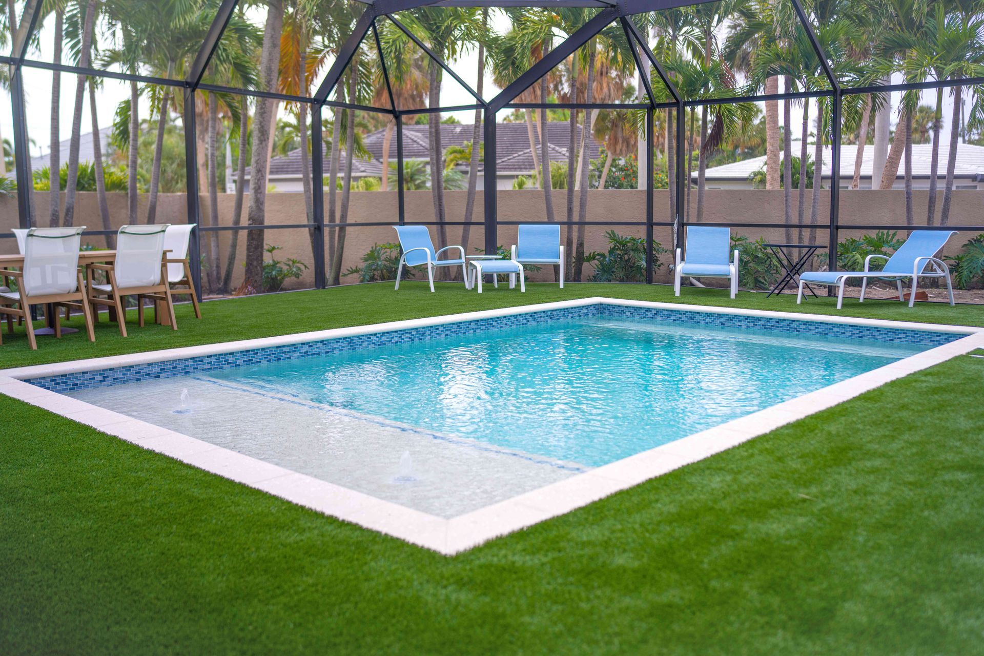 Outdoor swimming pool with white deck, blue water, and lounge chairs under a screened enclosure.