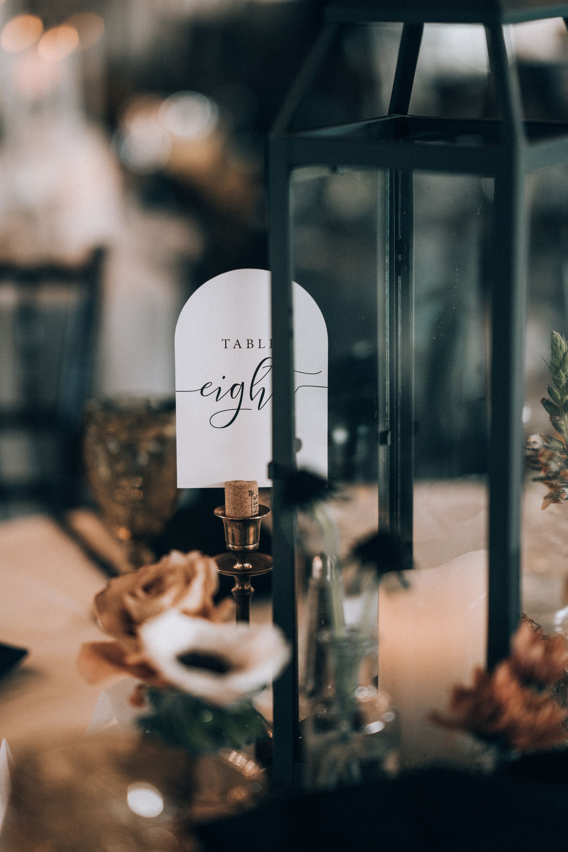 Table setting with a lantern, flowers, and a card reading 