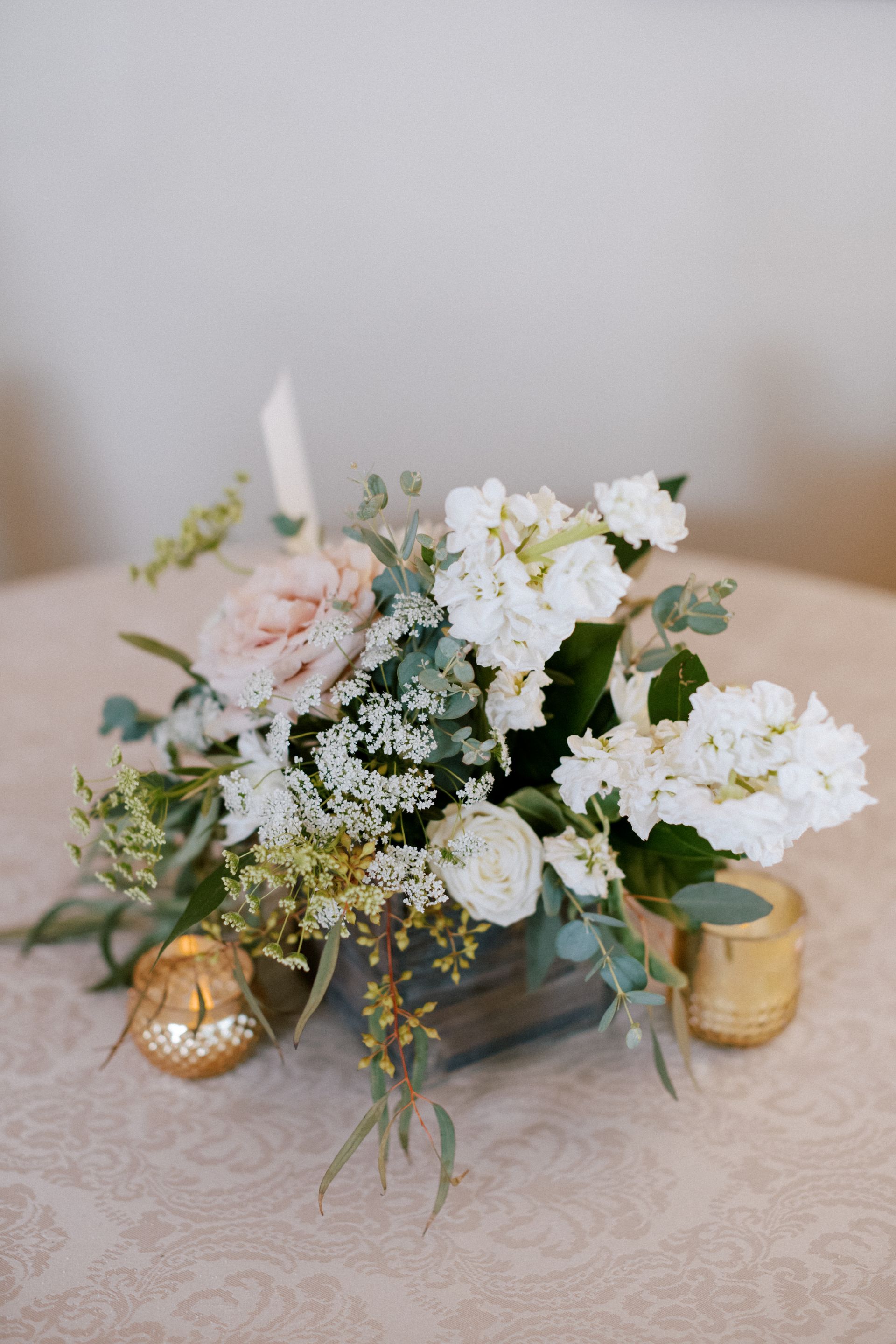 Floral arrangement in wooden box centerpiece with gold candle holders.