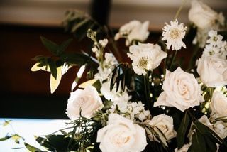 White roses and other white flowers in a floral arrangement with green foliage.