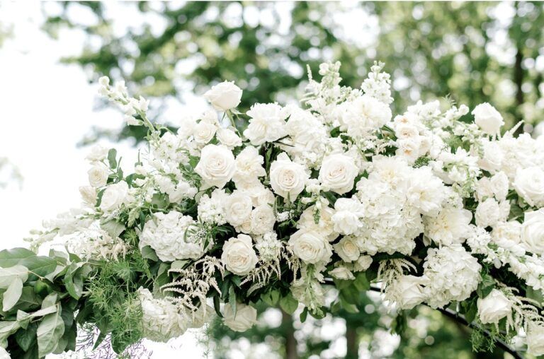 White floral arrangement on an arch, possibly a wedding.