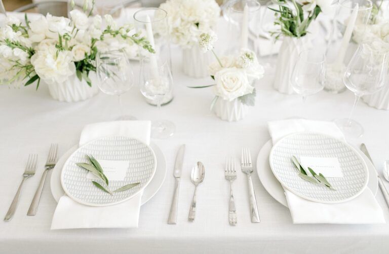 Elegant white table setting with flowers, plates, silverware, and place settings.