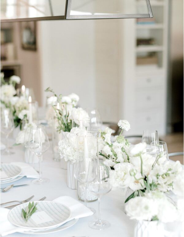 Elegant white dining table set with floral centerpieces and place settings.