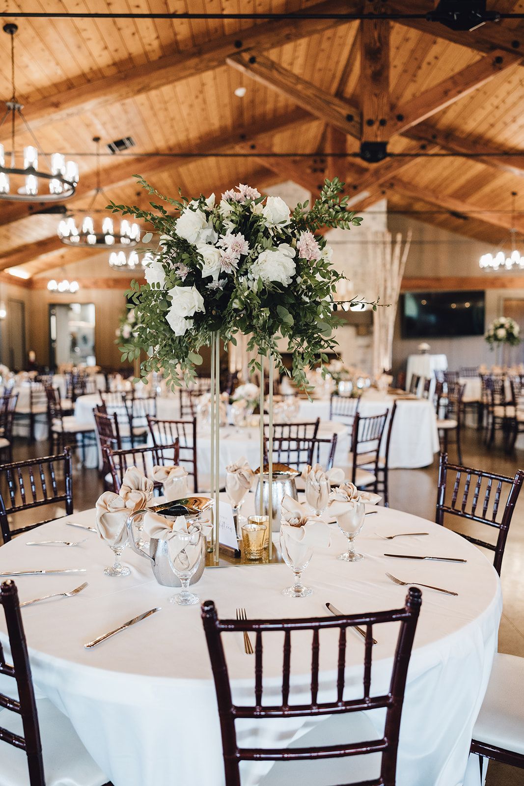 Round table with a tall floral centerpiece, set for a wedding reception.