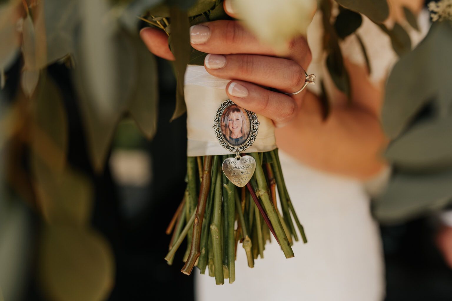 Bride holding bouquet with photo charm.