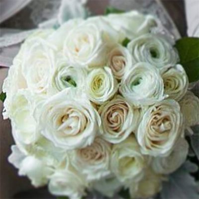 White rose bouquet, mostly in focus, held by a person.