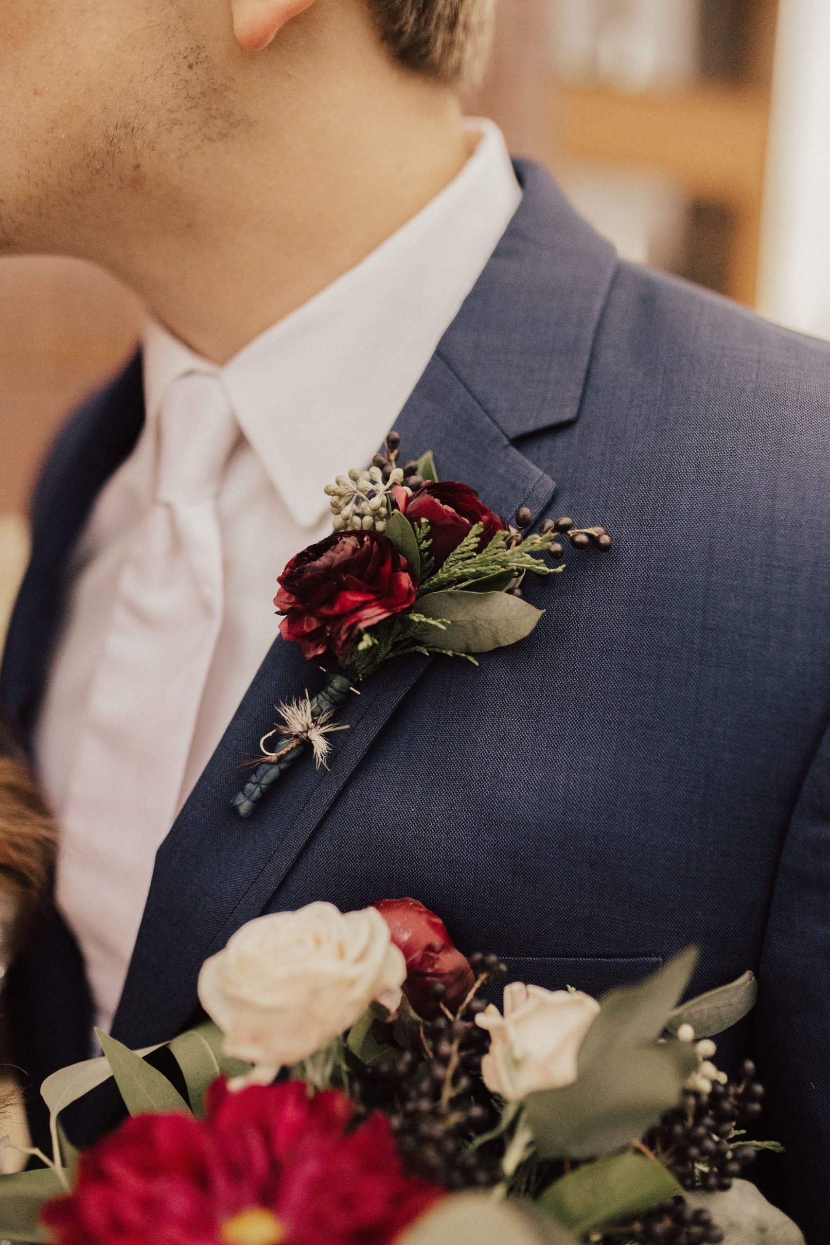 Man in blue suit with burgundy boutonniere, white shirt, and pink tie.