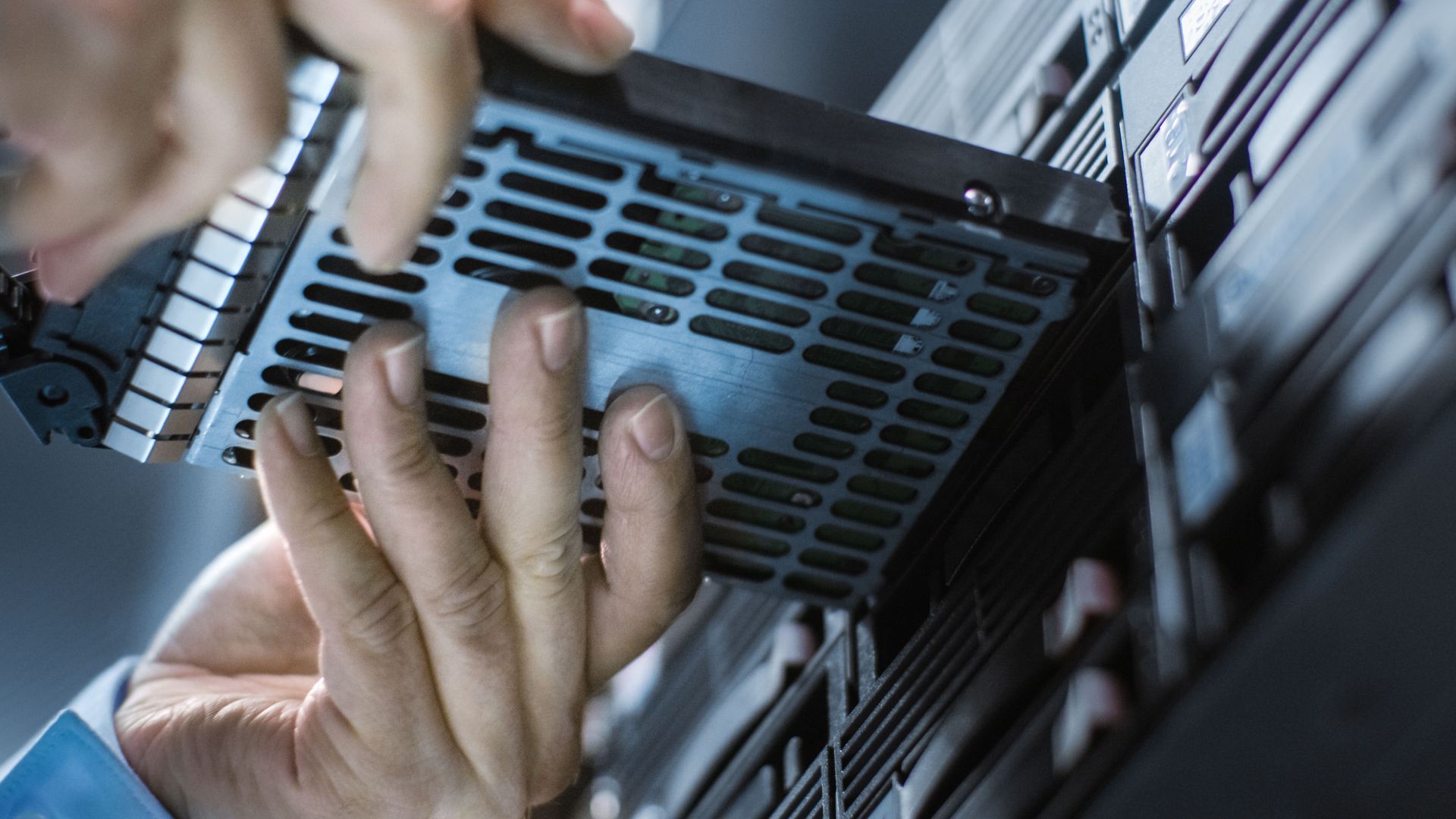 A person is installing a hard drive into a server.