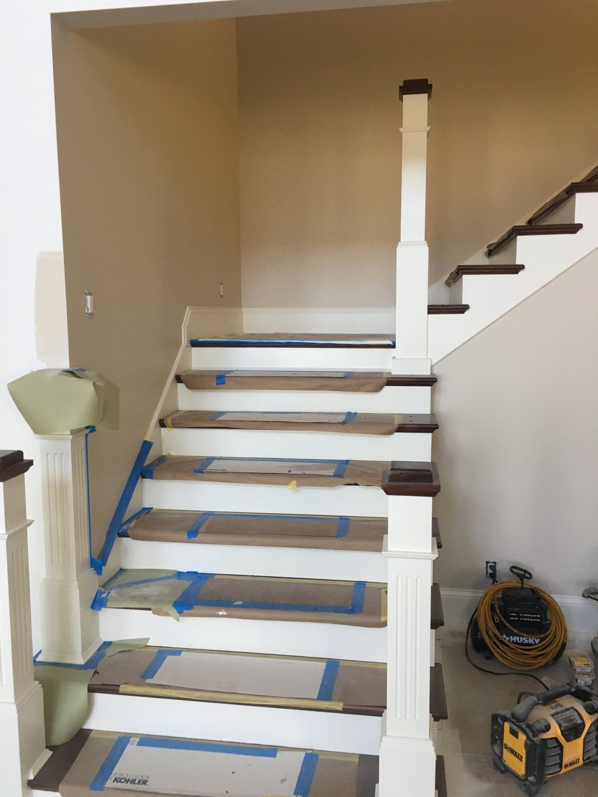 Indoor staircase under renovation, with blue painter’s tape on steps and tools on the floor.