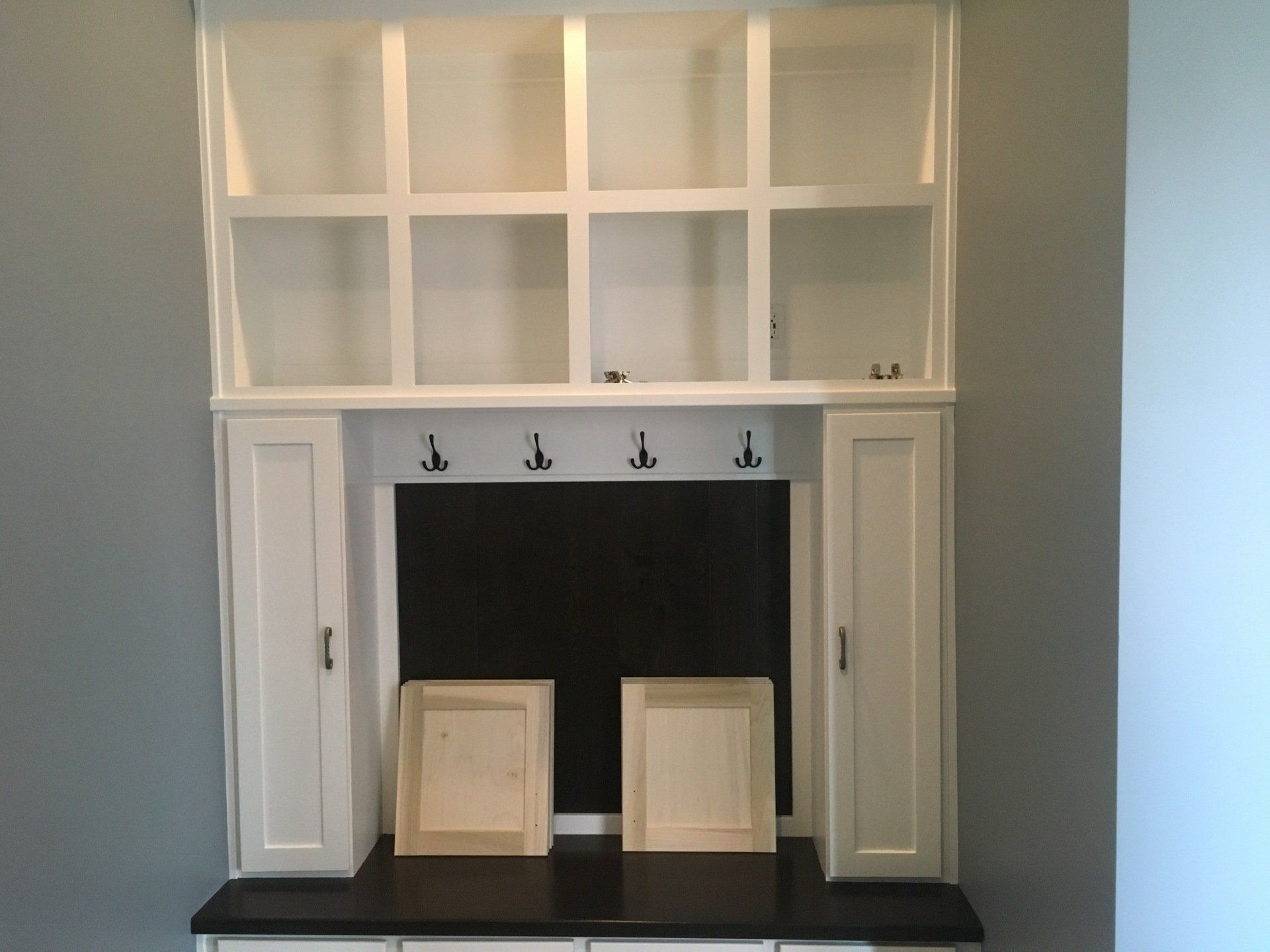 White built-in fireplace mantel with shelves and two small framed pieces on the hearth against a light blue wall