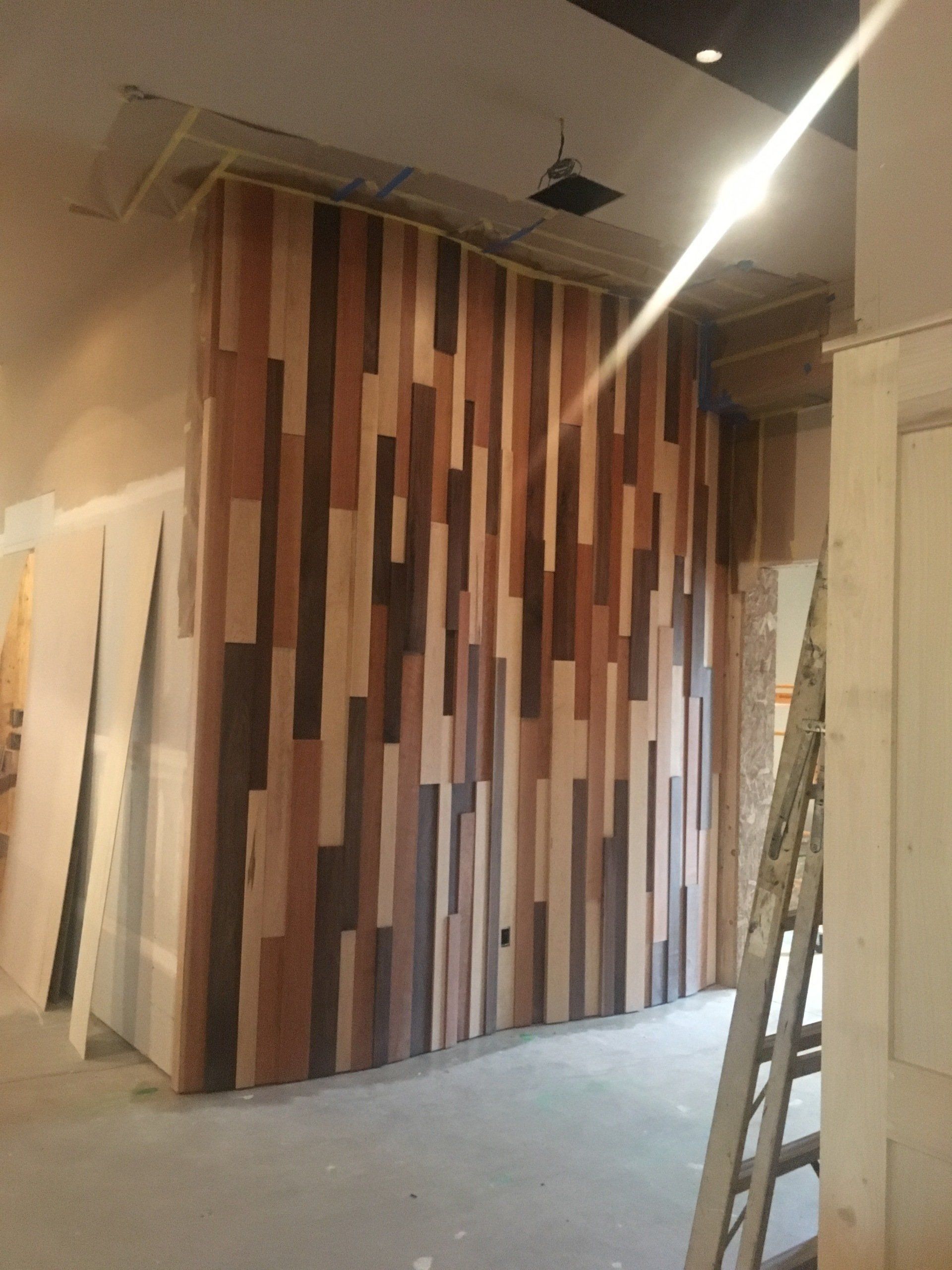 Interior under renovation with a tall wood slat accent wall and a ladder in the foreground