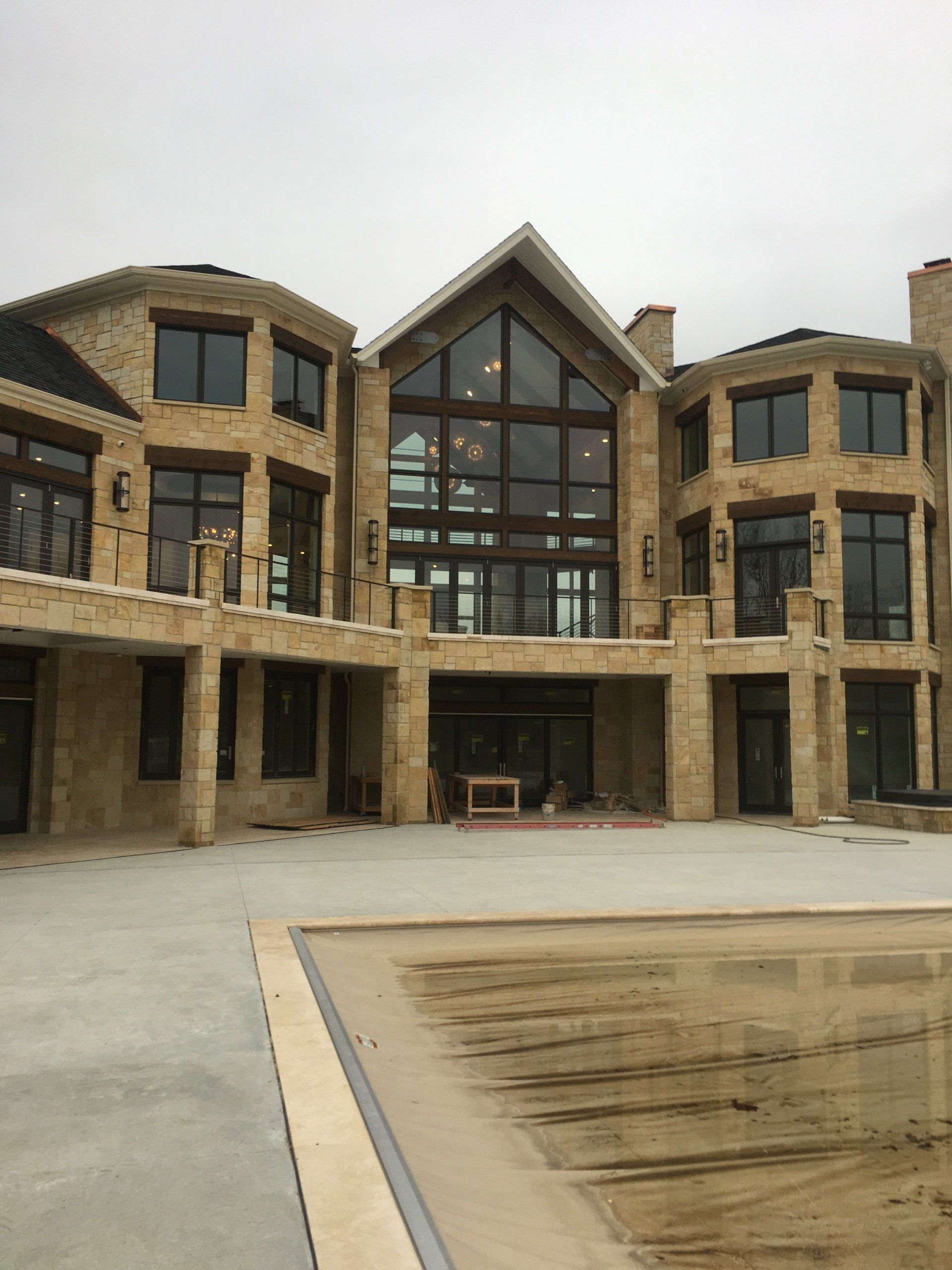 Large stone building with arched windows and a central glass entrance under construction or unfinished exterior
