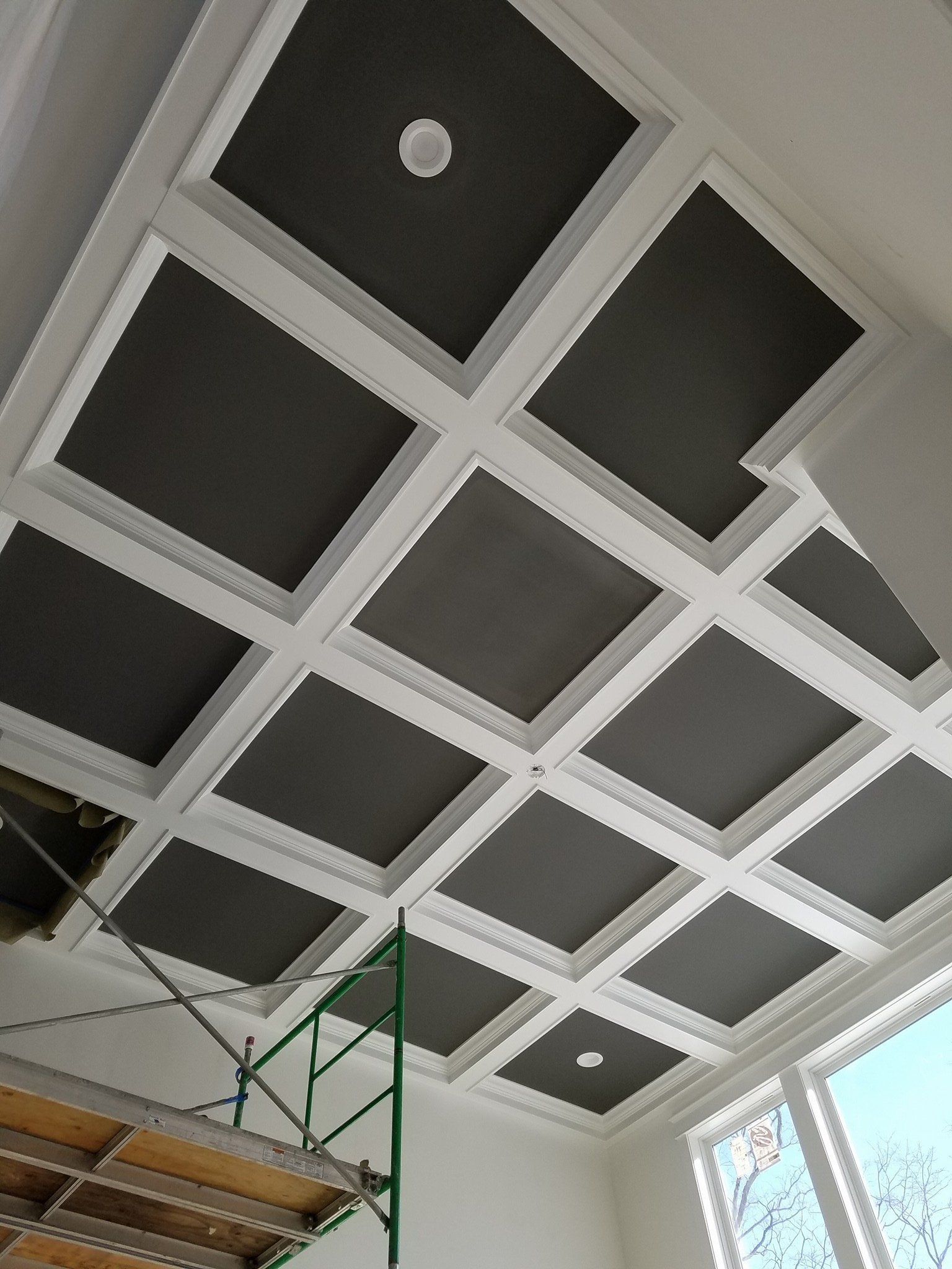 Ceiling with gray acoustic panels, white beams, and scaffolding in an indoor space