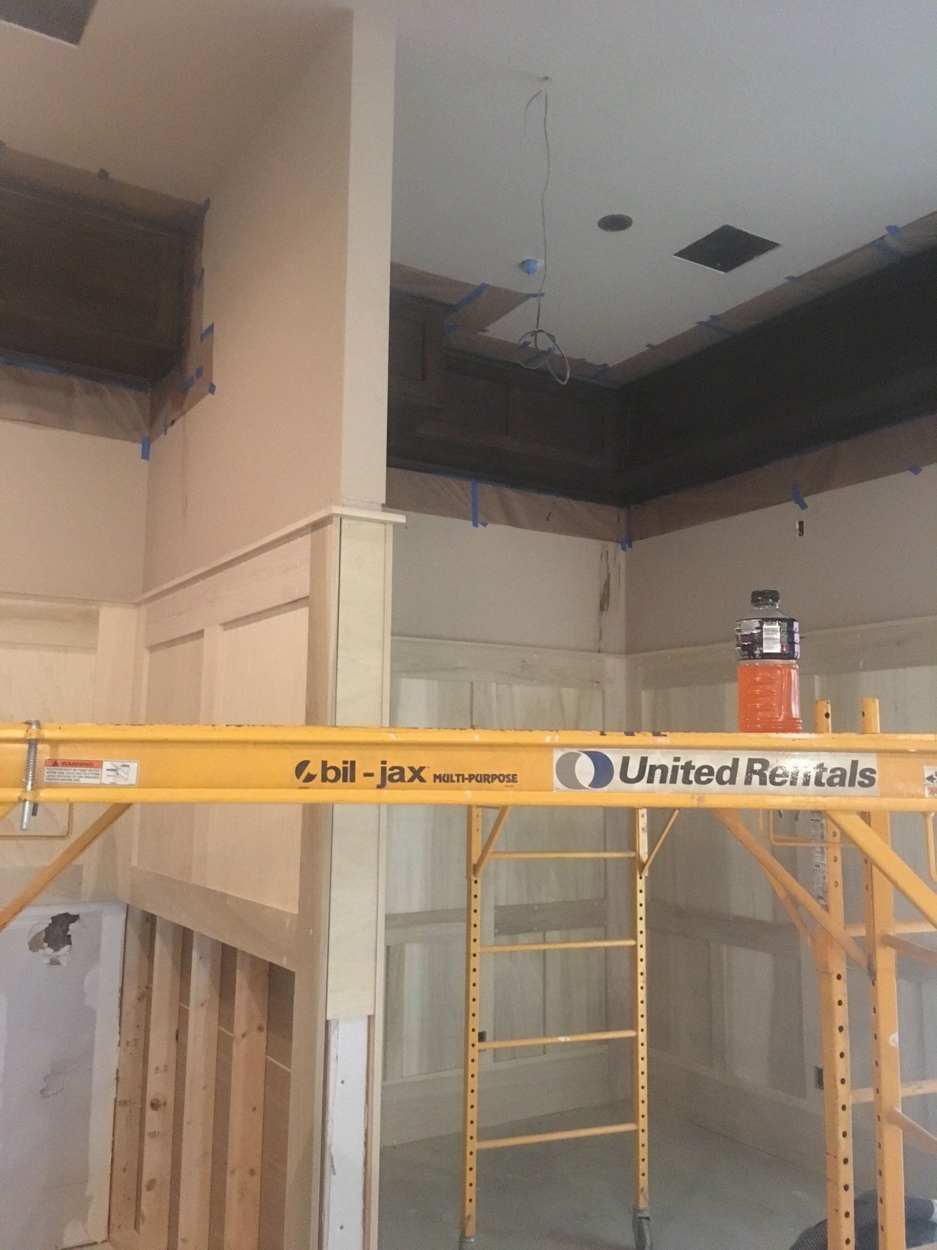 Construction site with scaffolding and ladders inside a room with high ceiling openings.