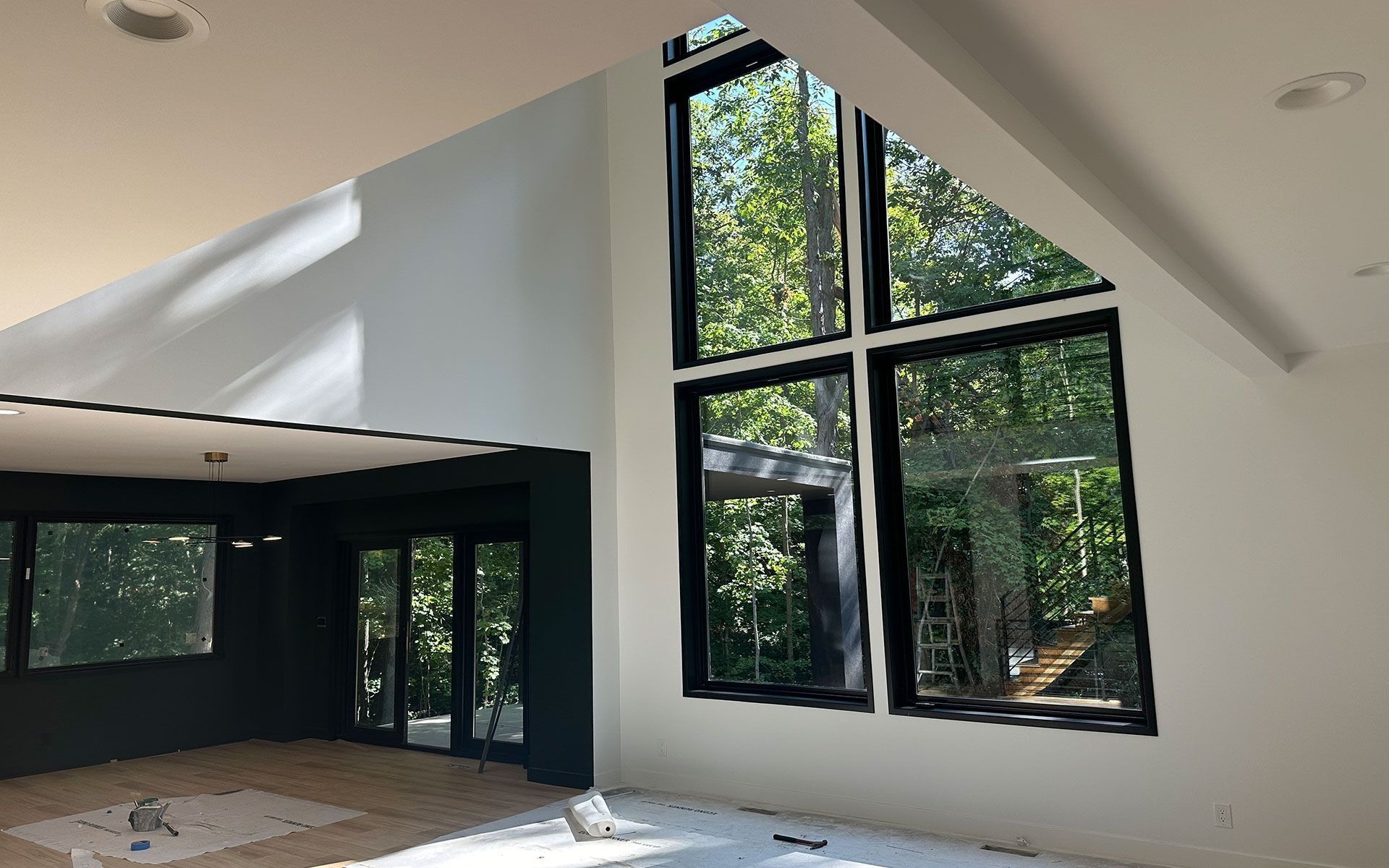 Empty modern living room with black-framed floor-to-ceiling windows and sloped white ceiling