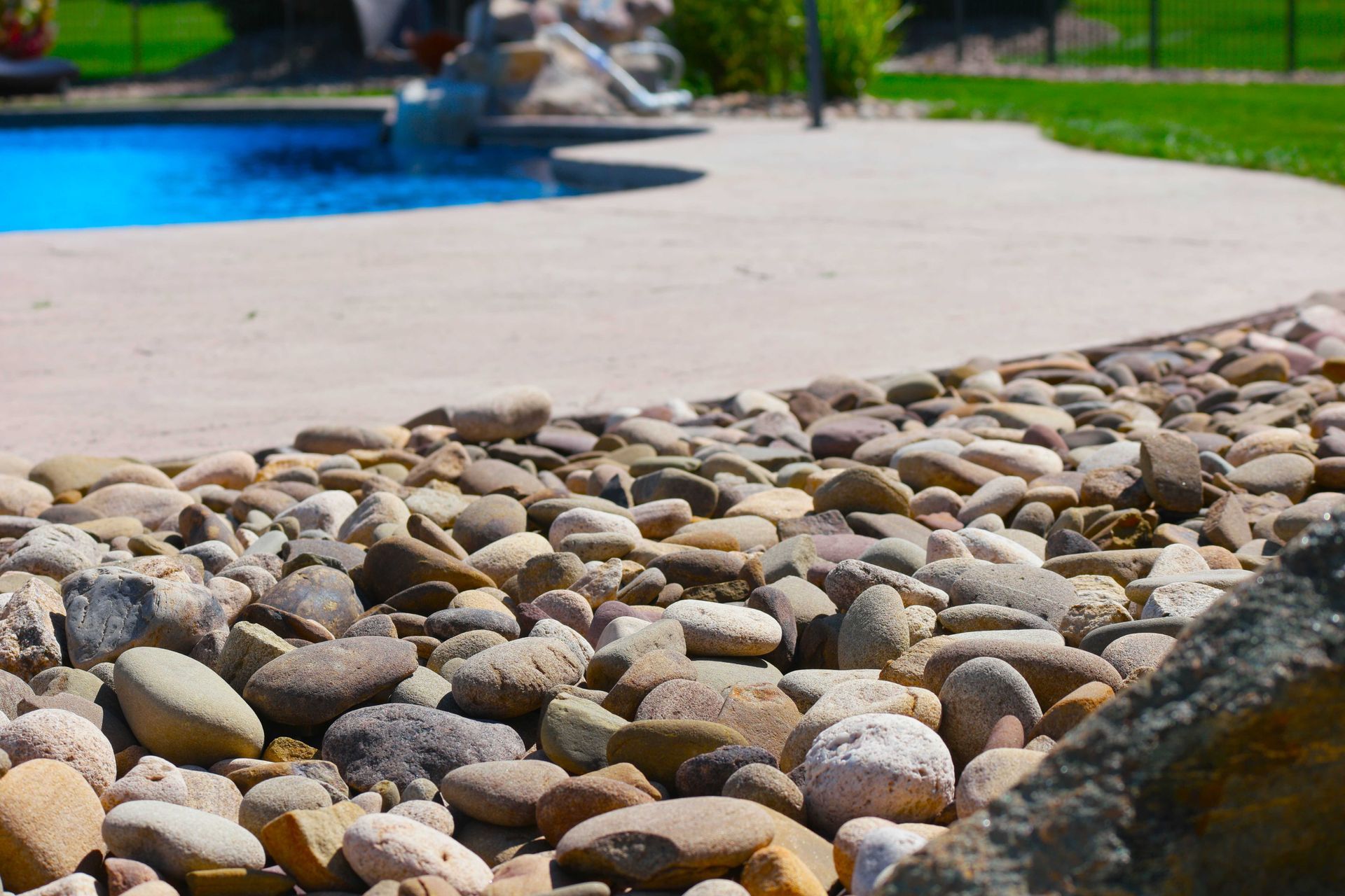 decorative stone border along a concrete patio, with a blue pool in the background