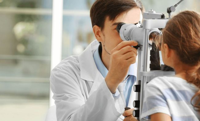 A doctor is examining a little girl 's eye