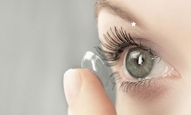 A woman is putting a contact lens in her eye
