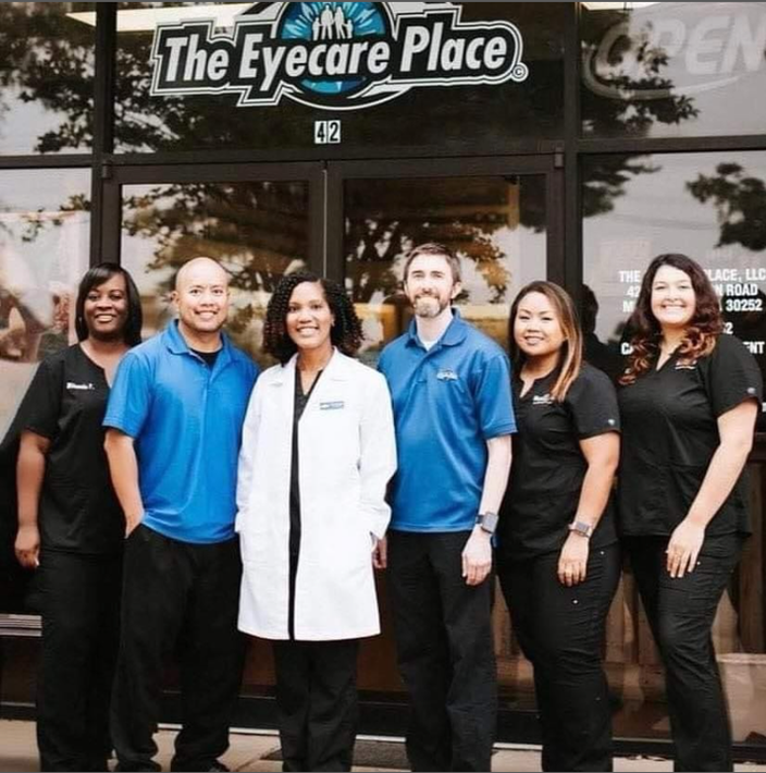 Group of six eye care professionals posing in front of their office, 