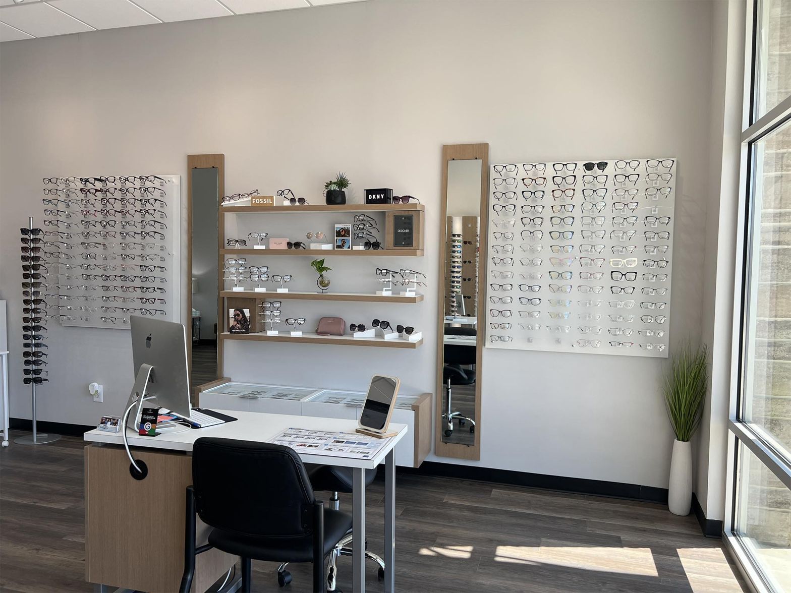 Optical shop interior with eyeglasses displays, a desk, and a large window.
