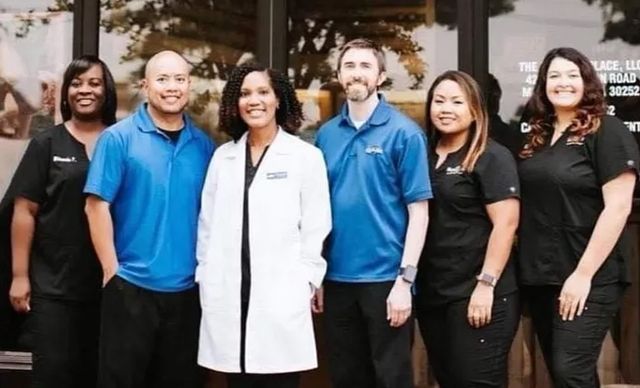 Medical staff in blue and black uniforms stand outside a building with glass doors.