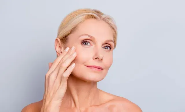 A smiling woman is touching her beautiful face after her EXION Skin Solutions treatment