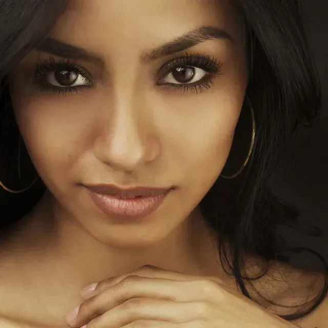 A close up of a woman 's face with her hand on her chin