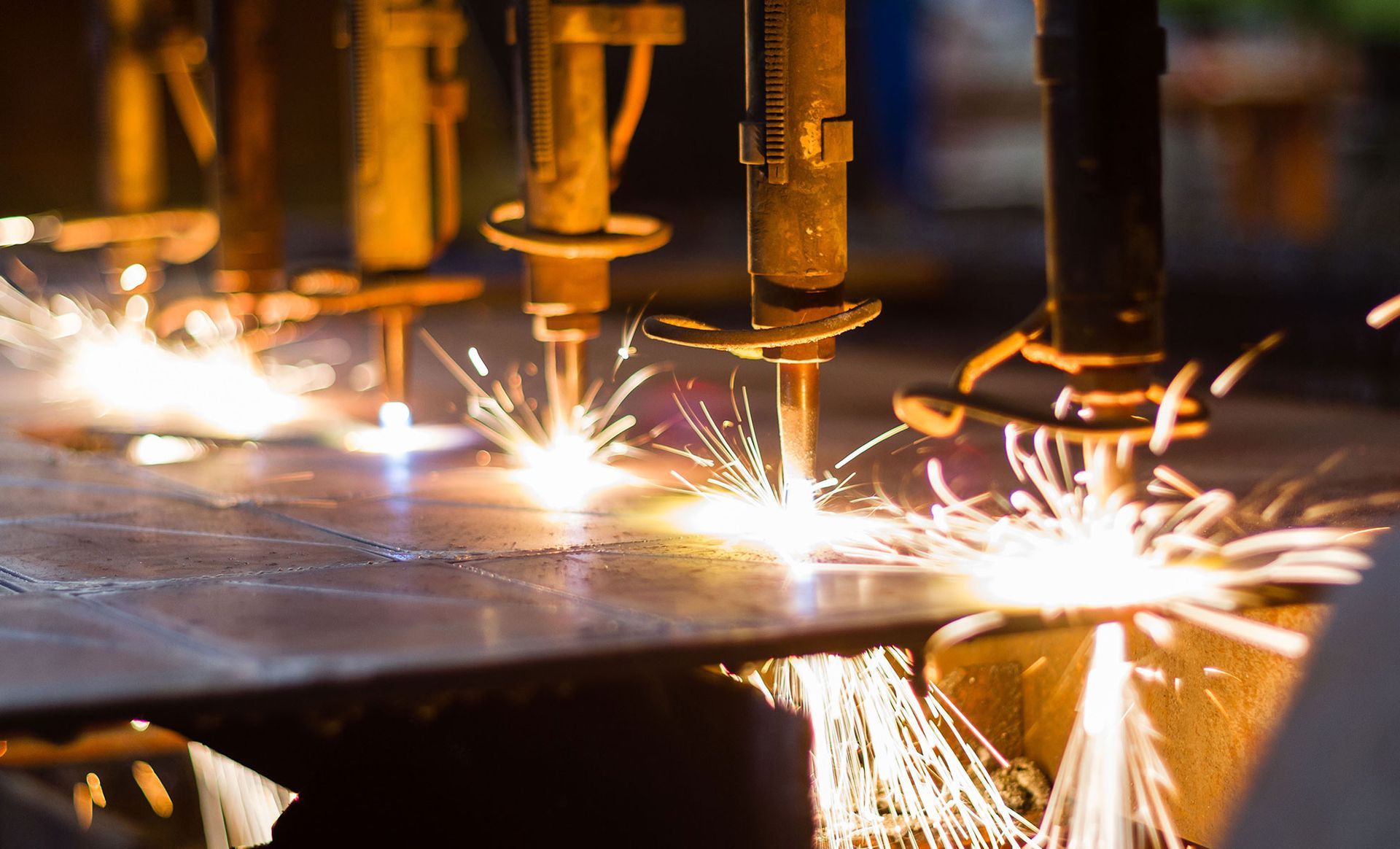 A machine is cutting a piece of metal with sparks coming out of it.