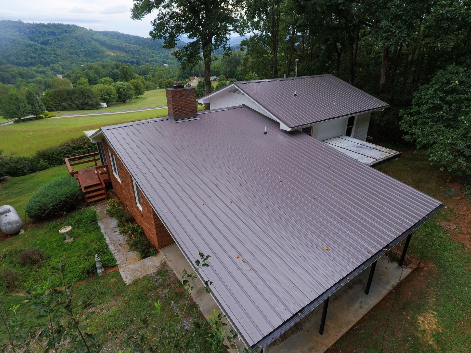 An aerial view of a house with a metal roof in the mountains.