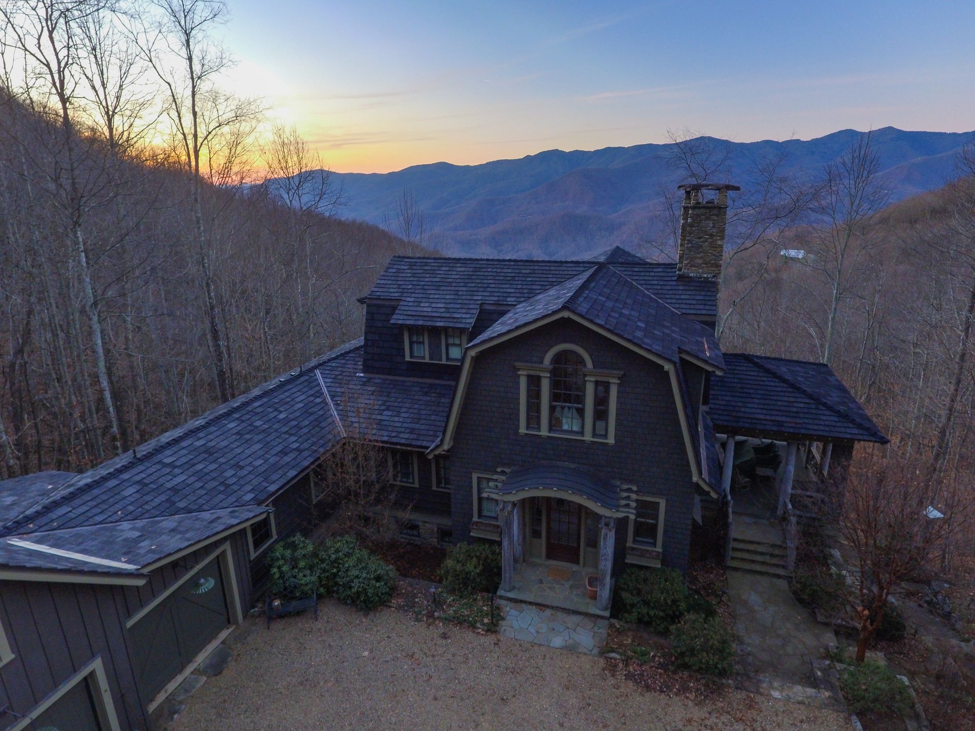 An aerial view of a large house in the mountains at sunset.