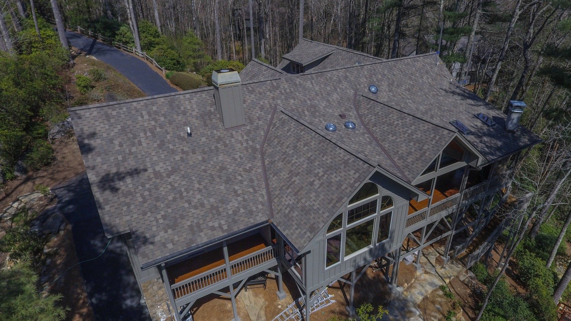 An aerial view of a large house in the middle of a forest.
