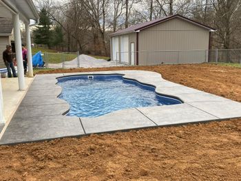 A swimming pool is being built in the backyard of a house