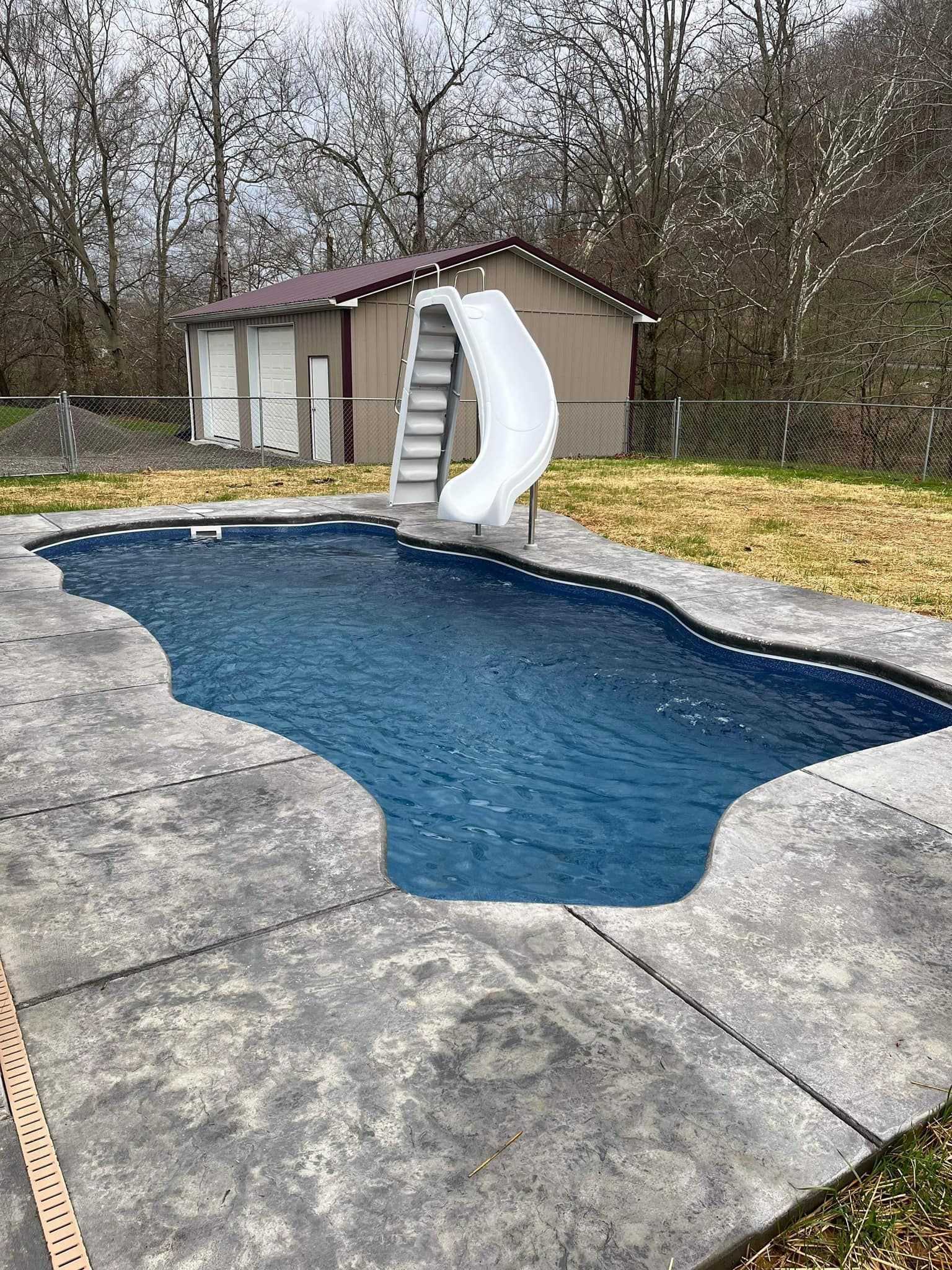 A large swimming pool with a slide and stairs in the backyard.