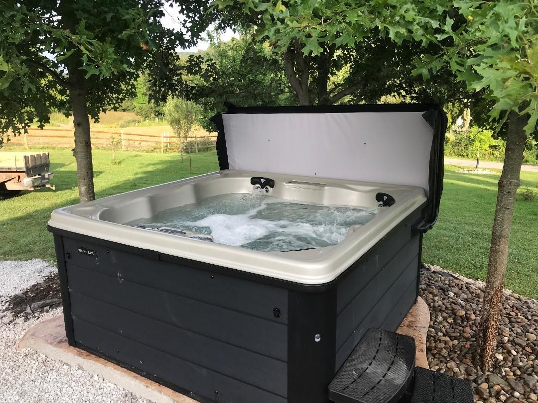 A hot tub is sitting in the middle of a yard surrounded by trees.