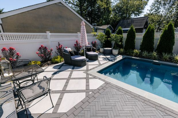 Backyard patio with a pool, seating area, and landscaping.