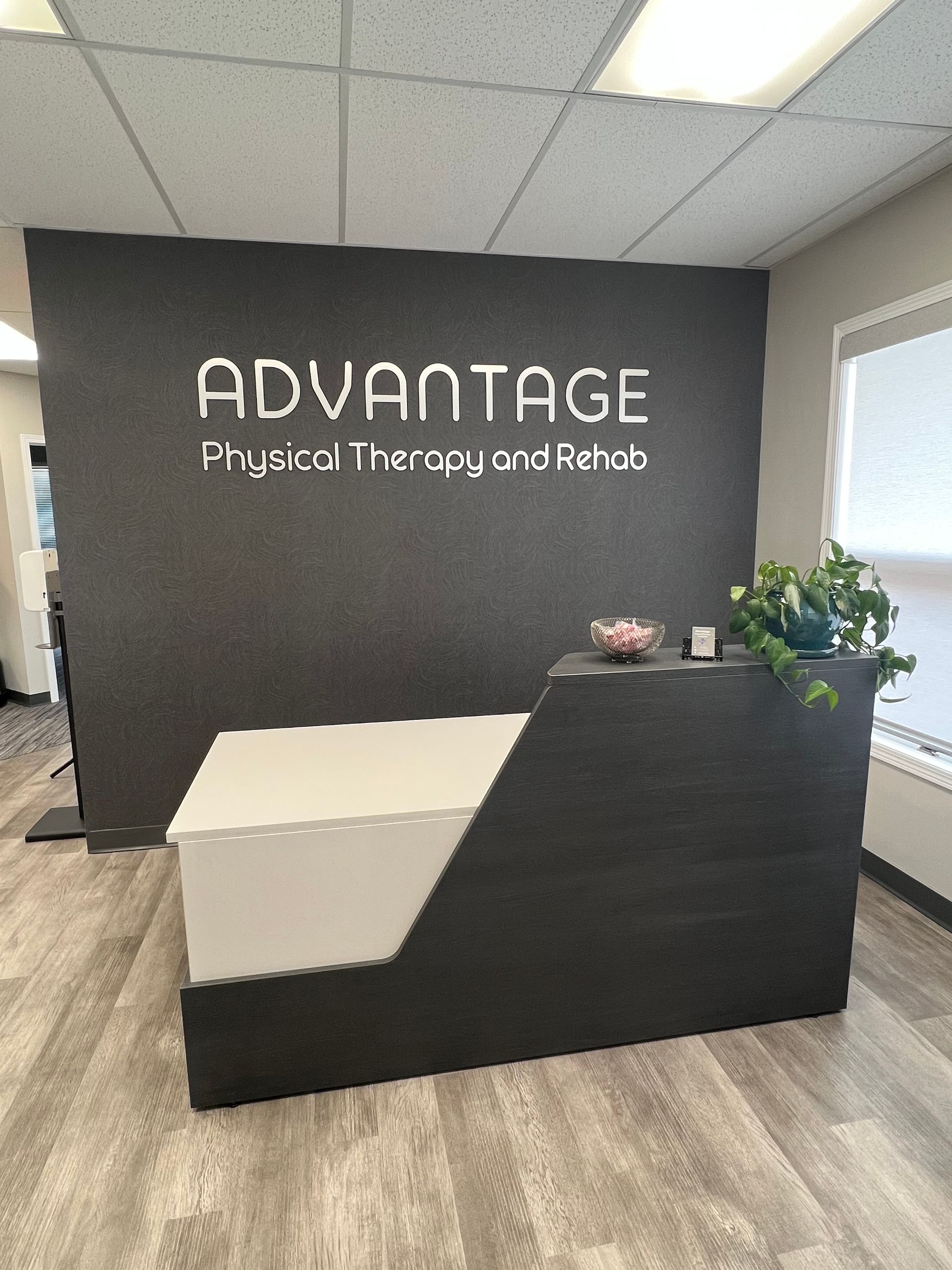 A reception desk in front of a wall that says `` advantage physical therapy and rehab ''.