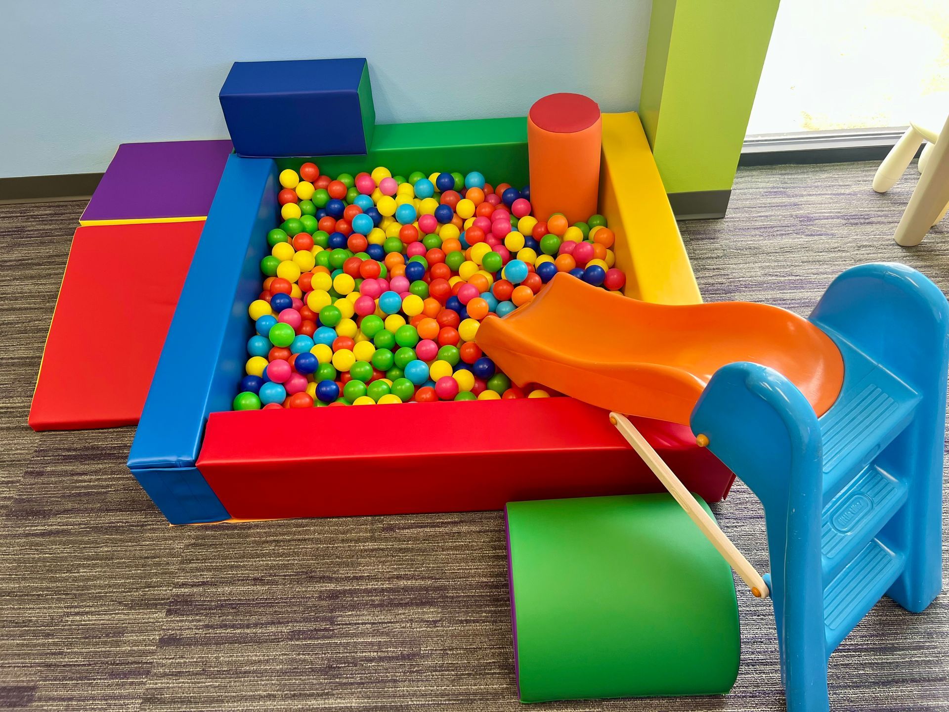 A colorful ball pit with a slide and stairs