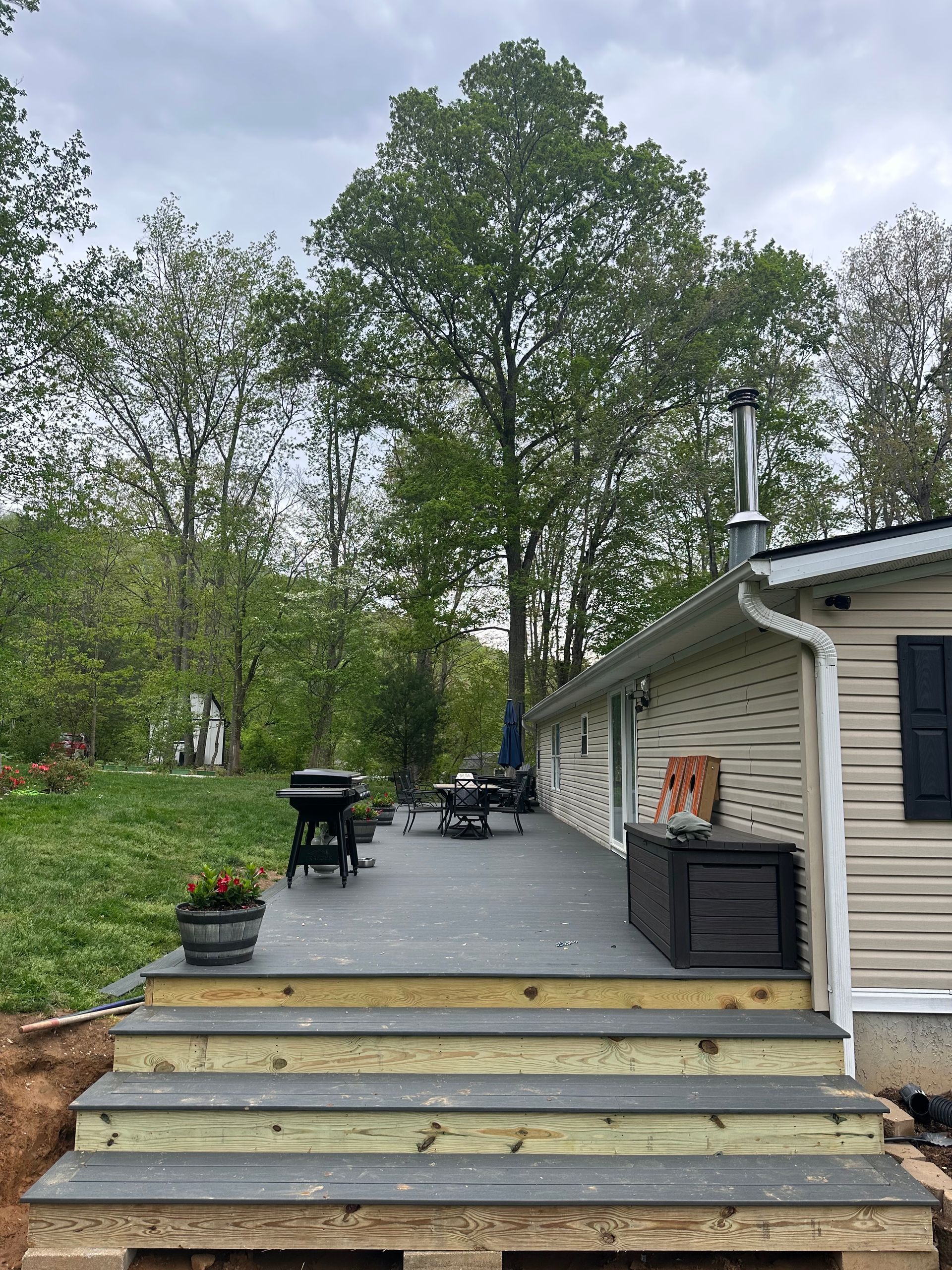 A wooden deck with stairs leading up to it is in front of a house.