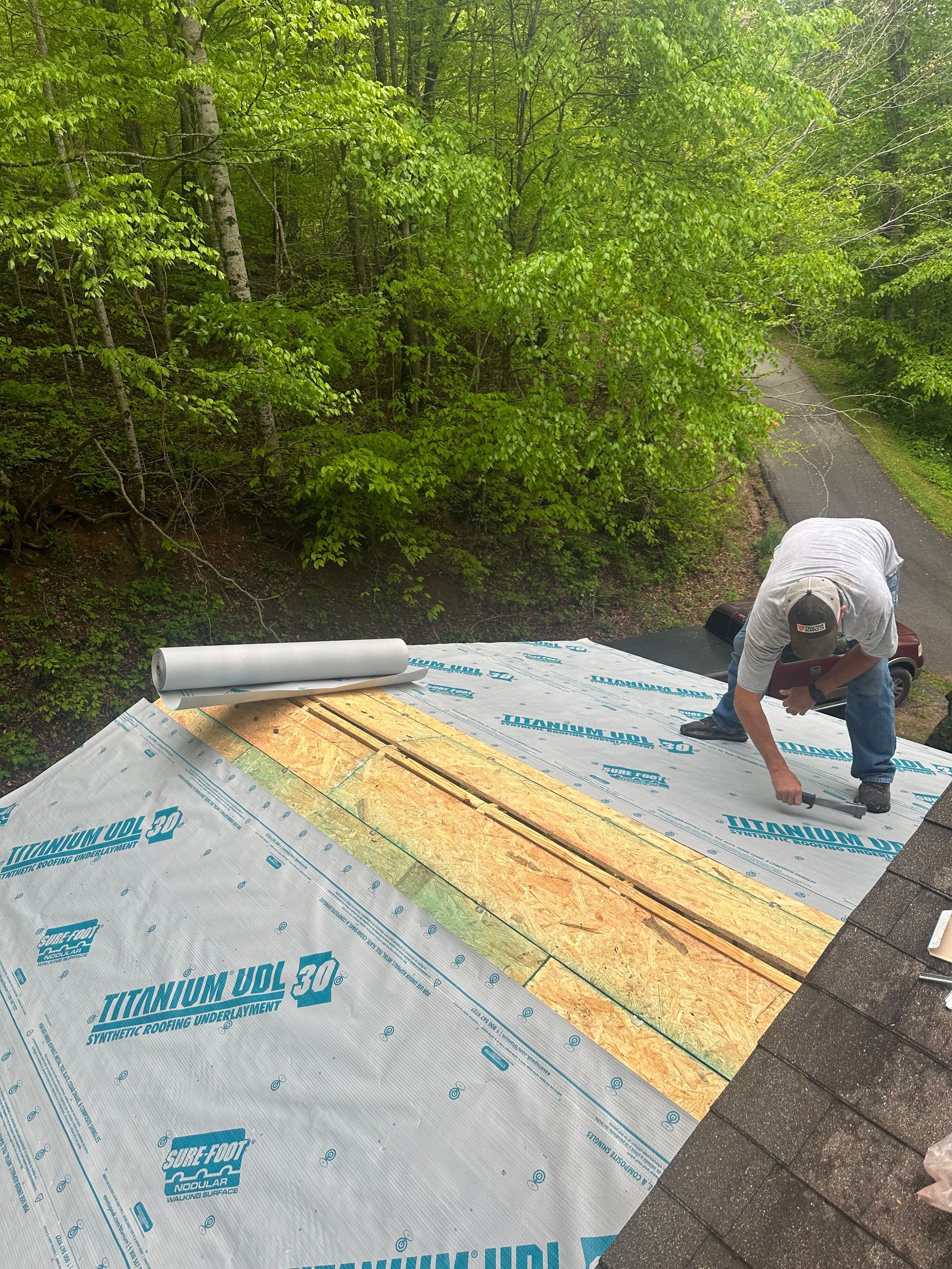 A man is working on a roof in the woods.