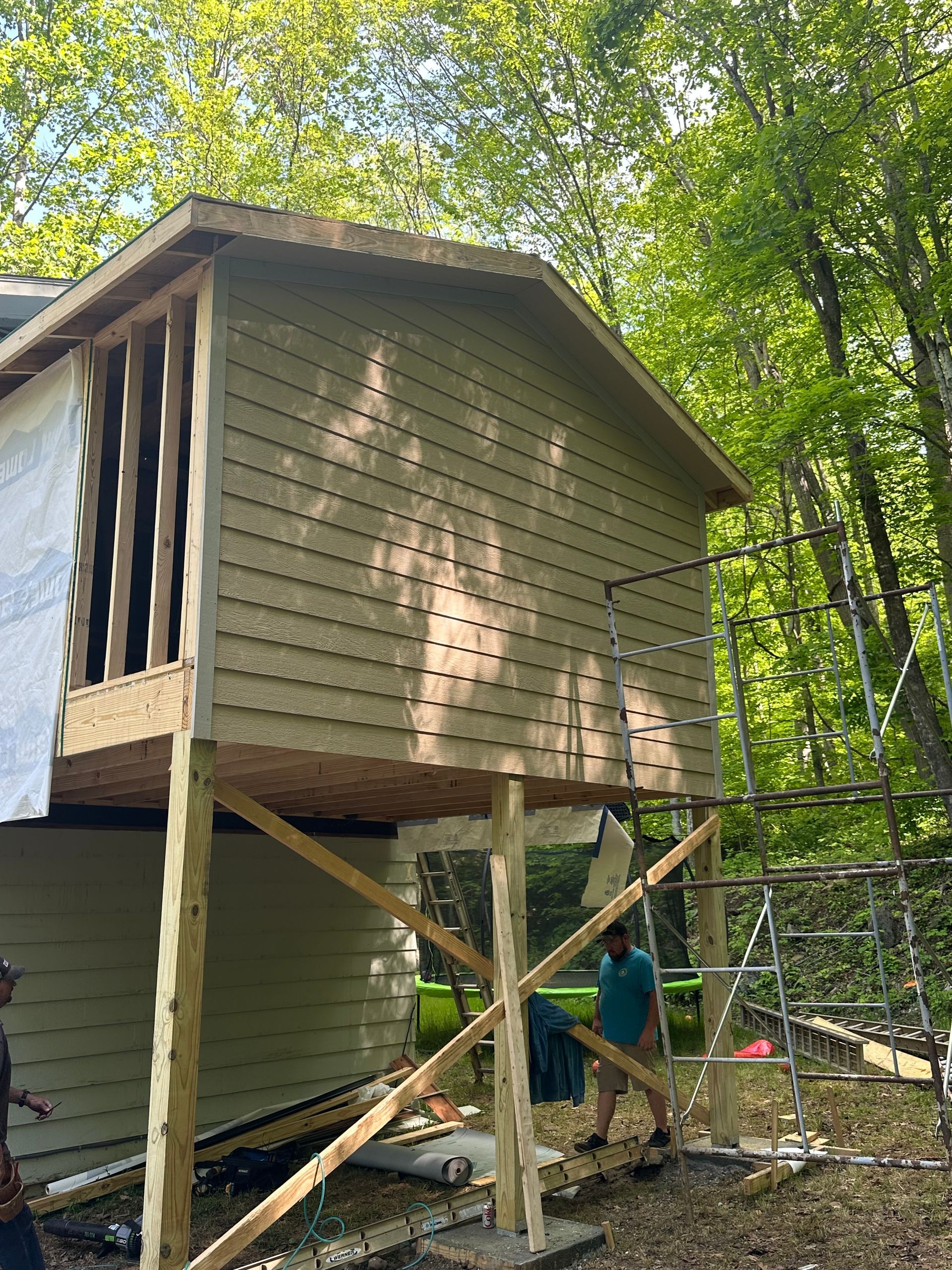 A man is standing in front of a house that is being built on stilts.