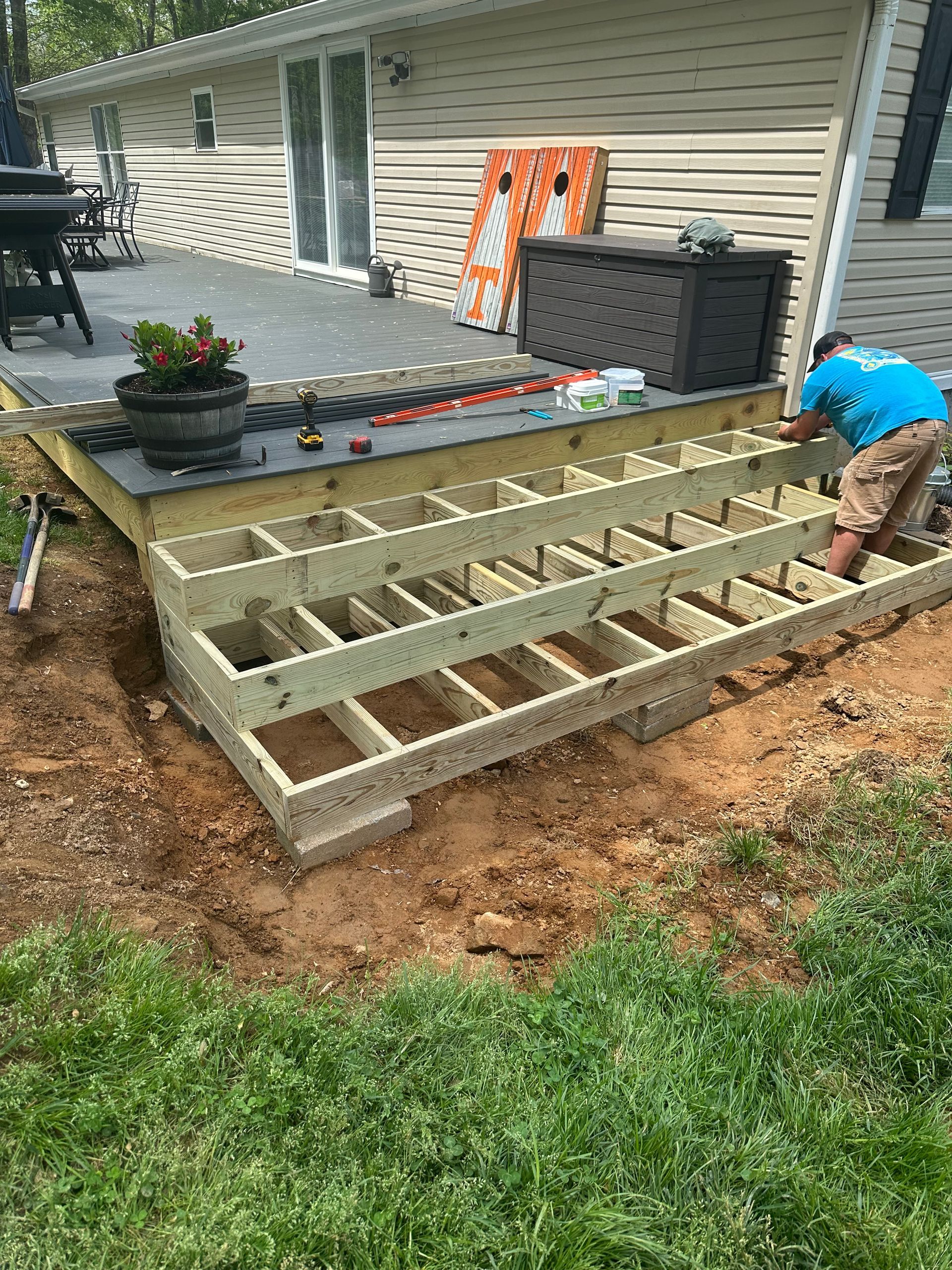 A man is working on a wooden deck in front of a house.