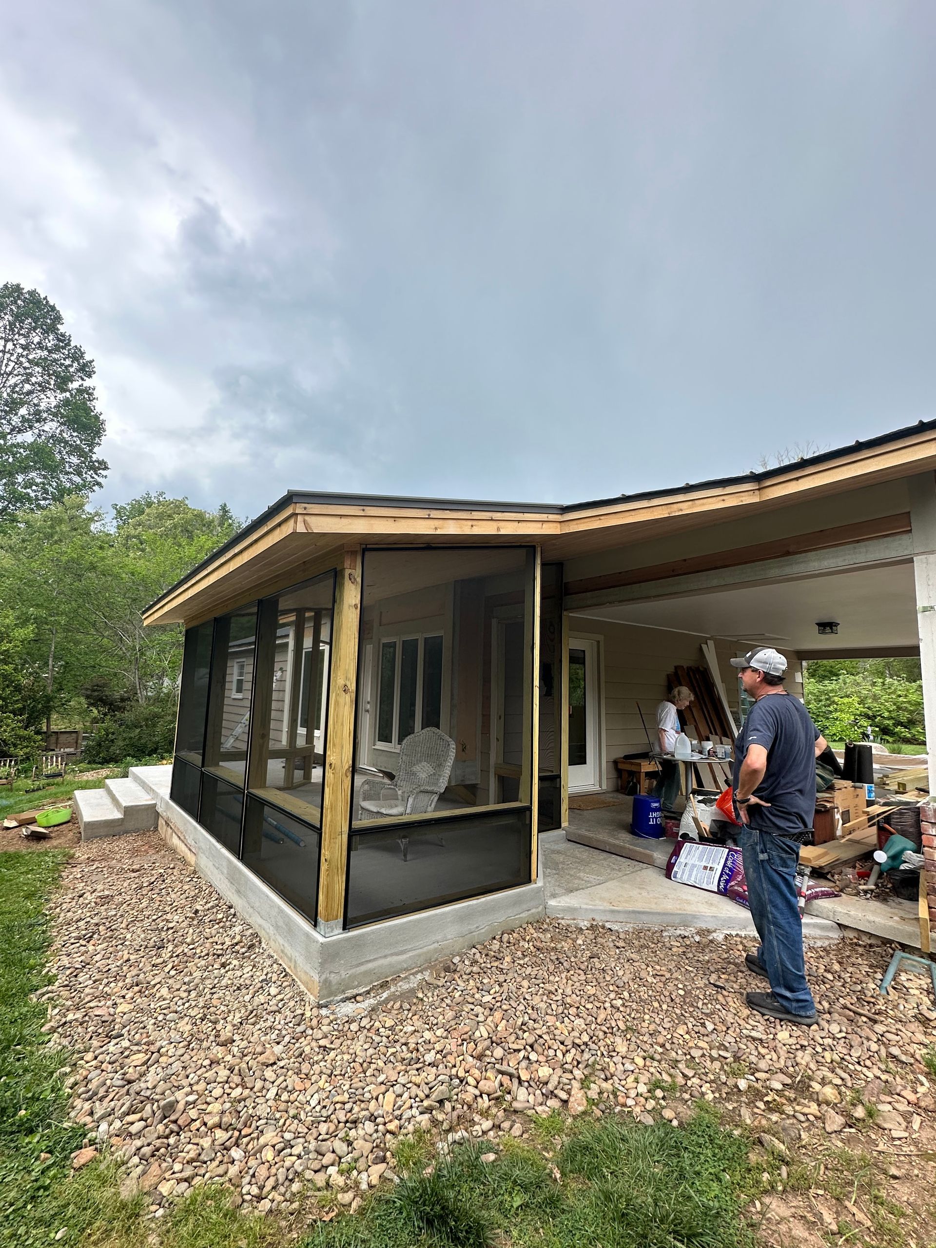 A man is standing in front of a screened in porch.
